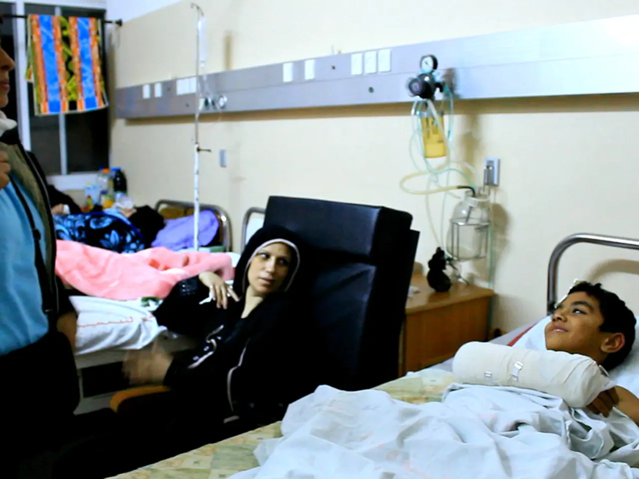 In the picture we can see inside view of the hospital with beds and patients on it and between the...