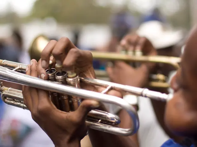 In this picture we can see two persons playing trumpets, we can see a blurry background here.