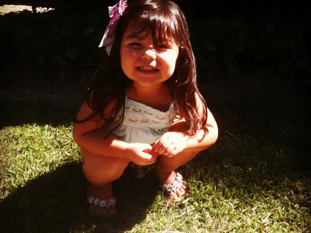 Here we can see a kid and a bowl on the grass.