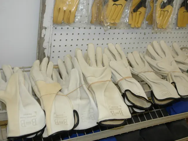 In this image on the rack there are many gloves. On the wall there are many yellow gloves in...