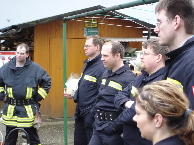 In this picture there is a group of men wearing a blue color fire safety dress, standing and...