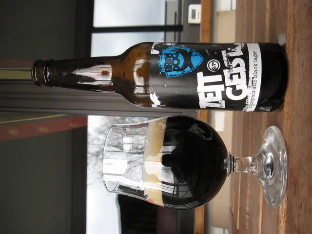 In this image we can see a bottle with a label on it and a glass with drink placed on the table.