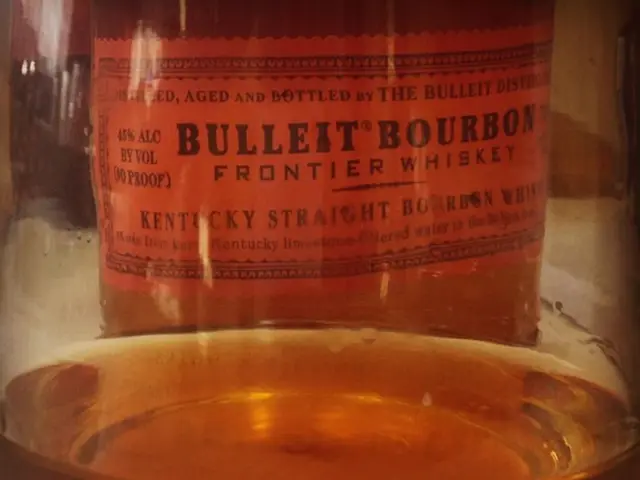 In this image we can see a bottle with a drink. And there is a label with something written on...