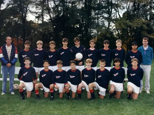This picture shows a group of people standing and a group of people kneeling and we see two men...