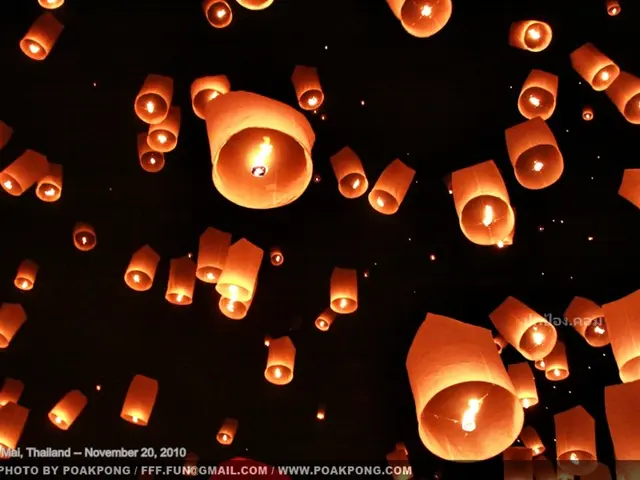 In this image we can see the night view of some sky lanterns and there is some text on the image.